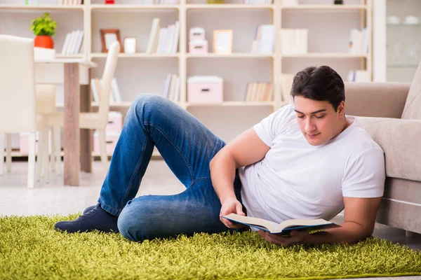 Hombre leyendo libro en casa en el suelo — Foto de Stock