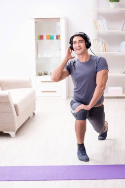 Adam evde spor yapıyor ve müzik dinliyor.