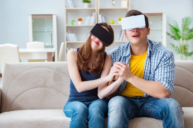 Genç bir aile sanal gerçeklik gözlükleriyle oyun oynuyor.