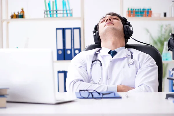 Glad upphetsad läkare lyssnar på musik under lunchen paus i ho — Stockfoto