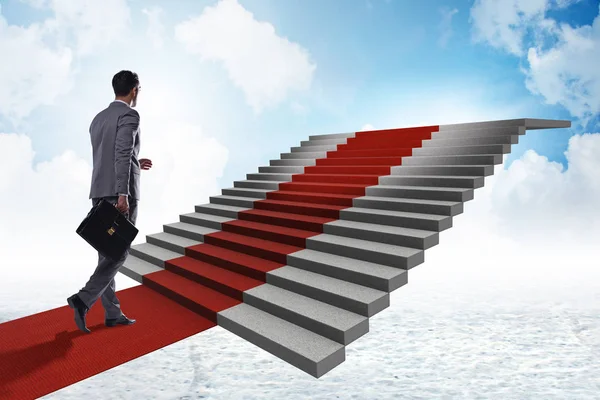 Joven hombre de negocios subiendo escaleras y alfombra roja en el cielo — Foto de Stock