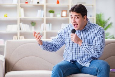 Evde karaoke yapan komik adam.