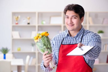 Çiçekçi asistanı bir demet çiçek veriyor.