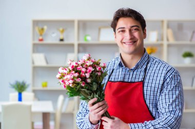 Çiçekçi asistanı bir demet çiçek veriyor.