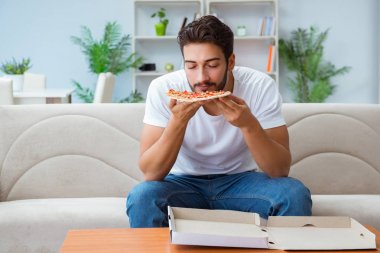 Pizza yiyen adam evde yemek yiyor, dinleniyor.