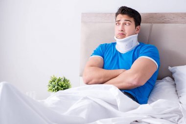 Yatakta boynu yaralanmış genç bir adam.