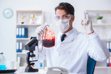 Hastane kliniğinde kan örnekleriyle çalışan bir doktor.