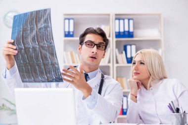 İki doktor teşhis için hastanın röntgen görüntülerini inceliyor.