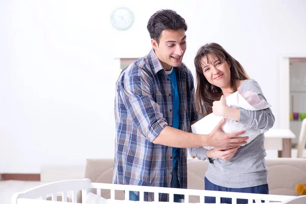 Padres jóvenes con su bebé recién nacido cerca de la cuna — Foto de Stock