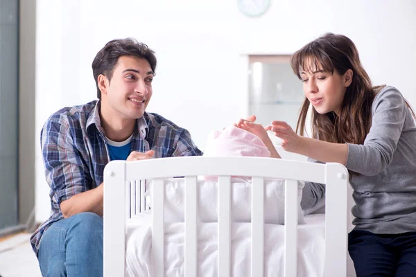 Padres jóvenes con su bebé recién nacido cerca de la cuna — Foto de Stock