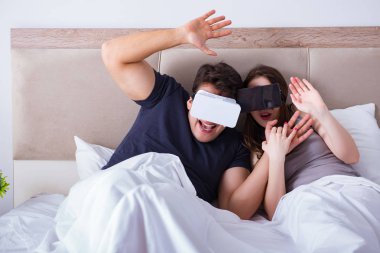 Yatakta sanal gerçeklik gözlüklü eş ve koca.