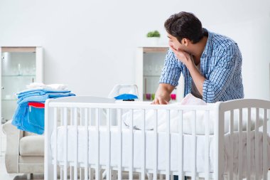 Genç baba yeni doğan bebeğe bakıyor.