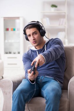 Genç adam evde bilgisayar oyunu oynuyor.