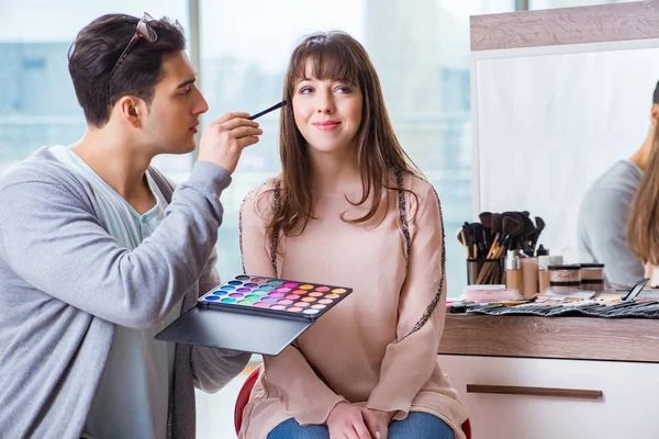 Man doing make-up for cute woman in beauty salon — Stock Photo, Image