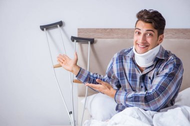 Evde koltuk değnekleriyle yatan yaralı bir adam var.