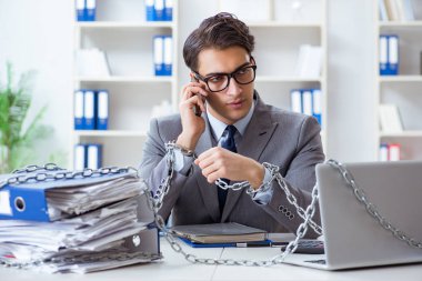 Ofis masasına zincirlenmiş meşgul bir çalışan.