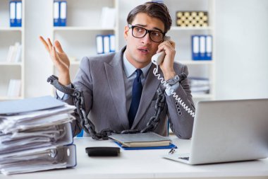 Ofis masasına zincirlenmiş meşgul bir çalışan.