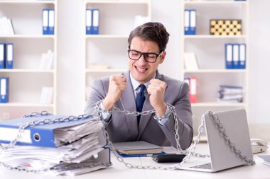 Ofis masasına zincirlenmiş meşgul bir çalışan.