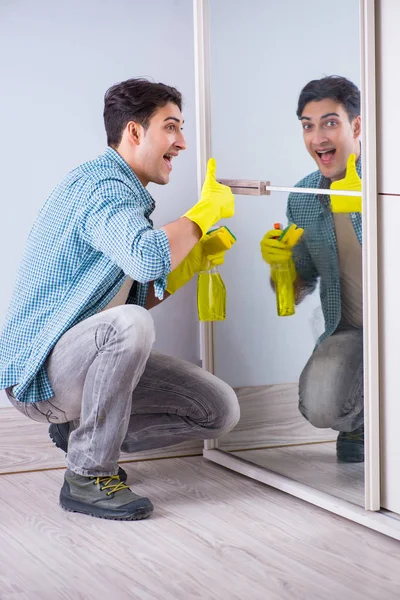 Mladý muž úklid zrcadlo doma hotel — Stock fotografie