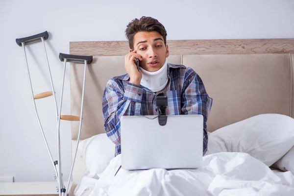 Injured man chatting online via webcam in bed at home