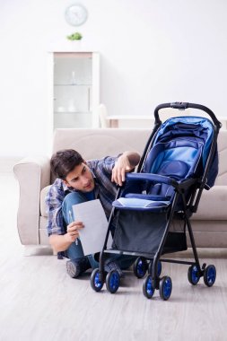 Genç baba evde bebek arabası monte ediyor.