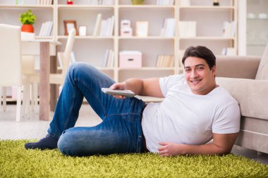 Evde yerde televizyon izleyen bir adam.