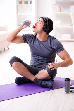 Adam evde spor yapıyor ve müzik dinliyor.