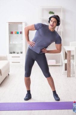 Adam evde spor yapıyor ve müzik dinliyor.