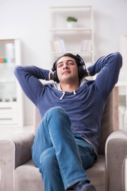 Genç adam evde müzik dinliyor.
