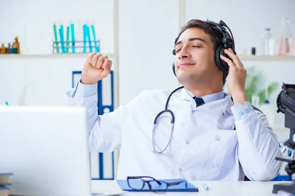 Happy excited doctor listening to music during lunch break in hospital