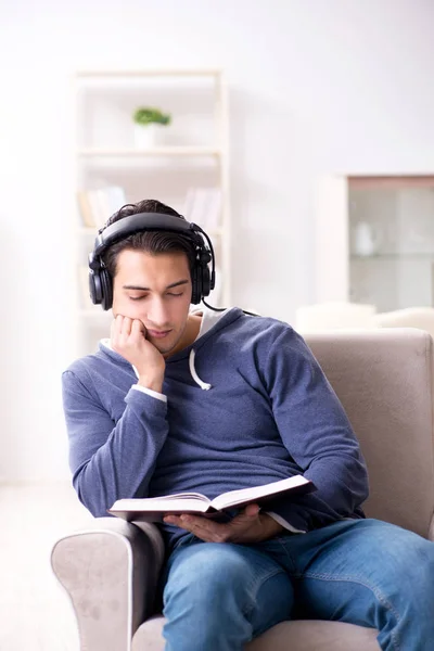 Joven leyendo libro y escuchando audio libro — Foto de Stock