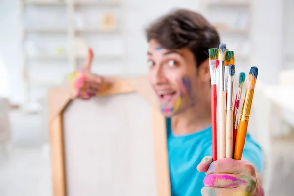 Jeune artiste drôle travaillant sur une nouvelle peinture dans son atelier — Photo