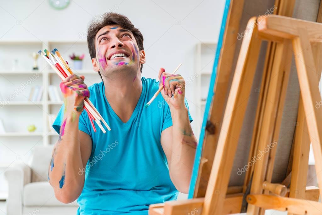 Young funny artist working on new painting in his studio