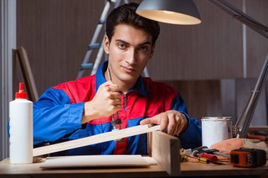 Genç adam ahşap parçaları DIY konseptinde yapıştırıyor.