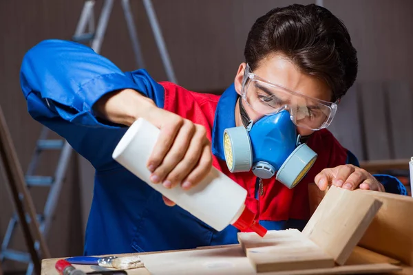 Young man gluing wood pieces together in DIY concept — Stock Photo, Image