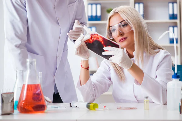 Mulher médica olhando para amostras de sangue no saco — Fotografia de Stock