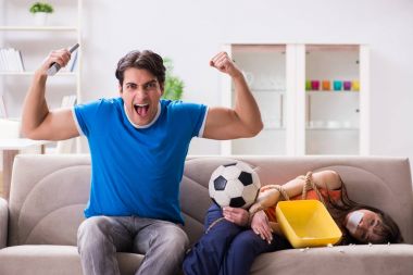 Adam spor maçı izlemek için karısını bağlıyor.