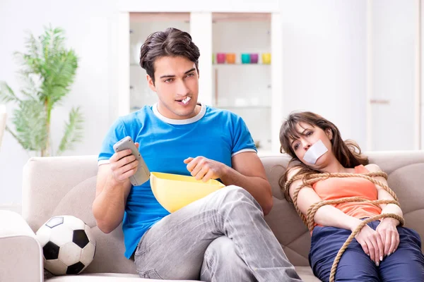 Adam spor maçı izlemek için karısını bağlıyor.