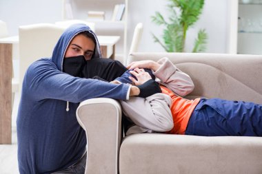 Silahlı bir adam evde genç bir kadına saldırıyor.