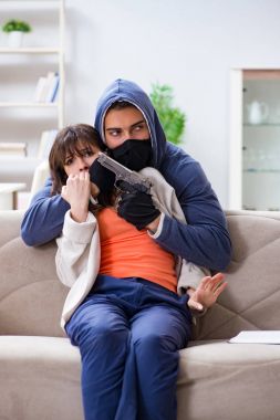 Silahlı bir adam evde genç bir kadına saldırıyor.