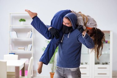 Silahlı bir adam evde genç bir kadına saldırıyor.