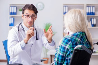 Tekerlekli sandalyedeki engelli kadın erkek doktoru ziyaret ediyor.