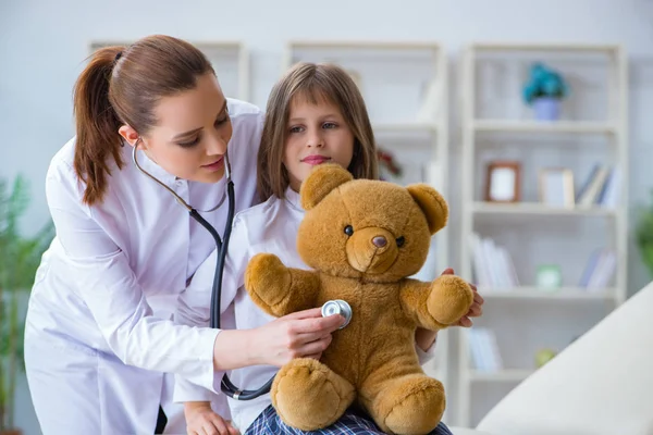 Kobieta lekarz egzaminowanie mało słodkie dziewczyna z zabawka niedźwiedź — Zdjęcie stockowe