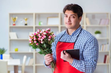 Çiçekçi asistanı bir demet çiçek veriyor.