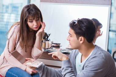 Güzellik salonunda güzel bir kadın için makyaj yapan adam.