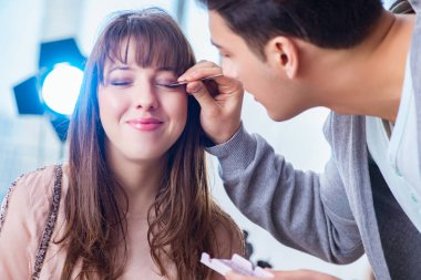 Güzellik salonunda güzel bir kadın için makyaj yapan adam.