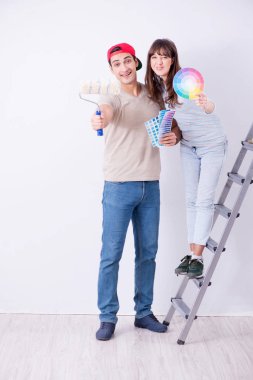 Genç bir aile evlerinde tadilat yapıyor. Duvarları boyuyor.