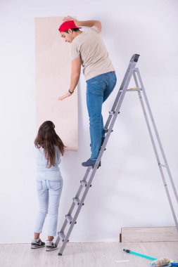 Genç bir aile yeni duvar kağıdıyla evde tadilat yapıyor.