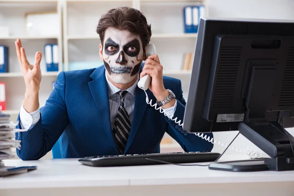 Businessmsn with scary face mask working in office