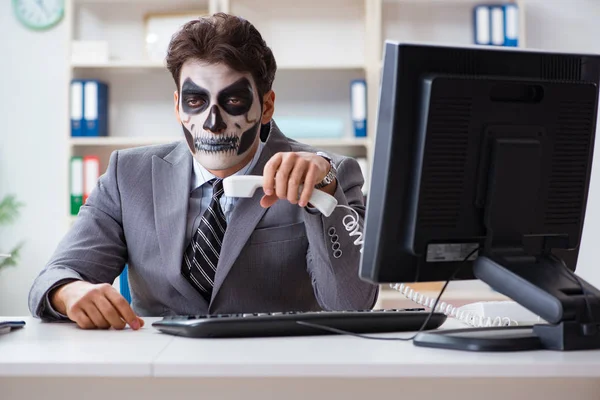 Businessmsn with scary face mask working in office